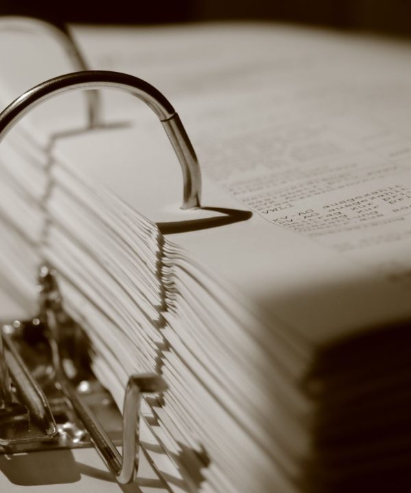 Detailed sepia close-up of a binder filled with documents, emphasizing texture.
